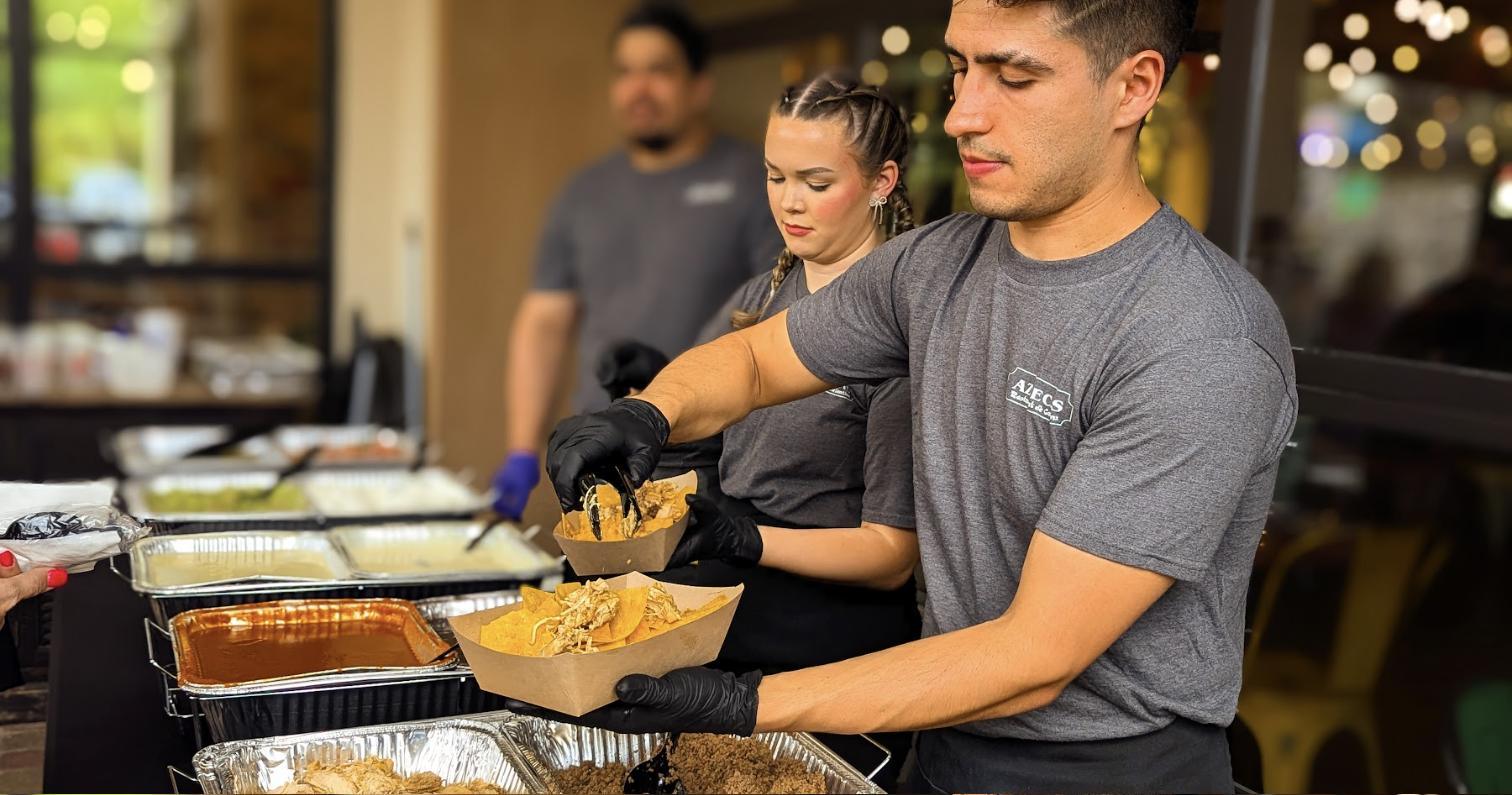 The Aztecas catering team serving from chafing trays at an event