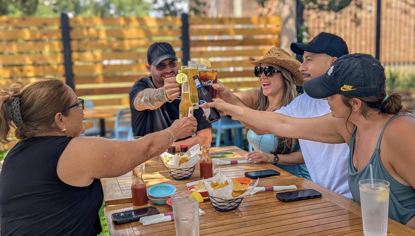 Friends raising margaritas together at an Aztecas table