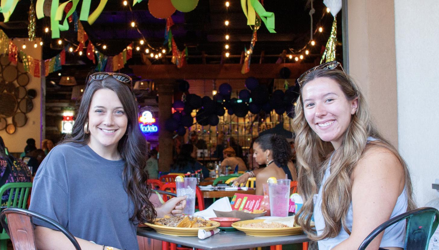Friends sharing plates and drinks in a busy Aztecas dining room