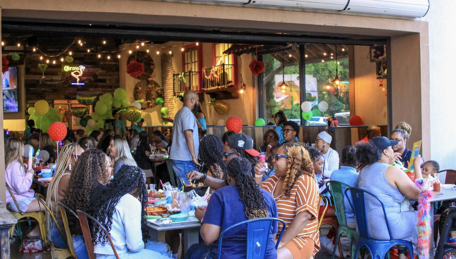 A packed Aztecas patio on a busy evening, tables full of guests under string lights