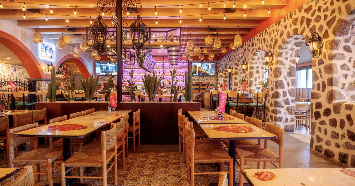 The Aztecas dining room under string lights with stone archways