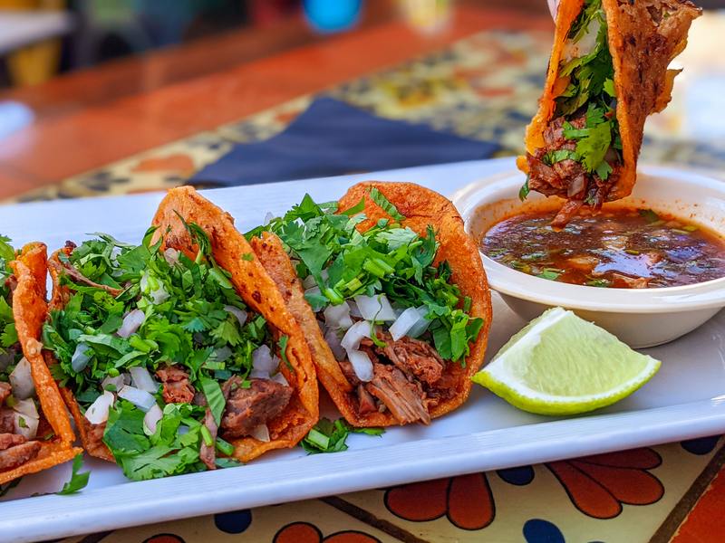 Birria tacos with cilantro, onion and a bowl of consommé