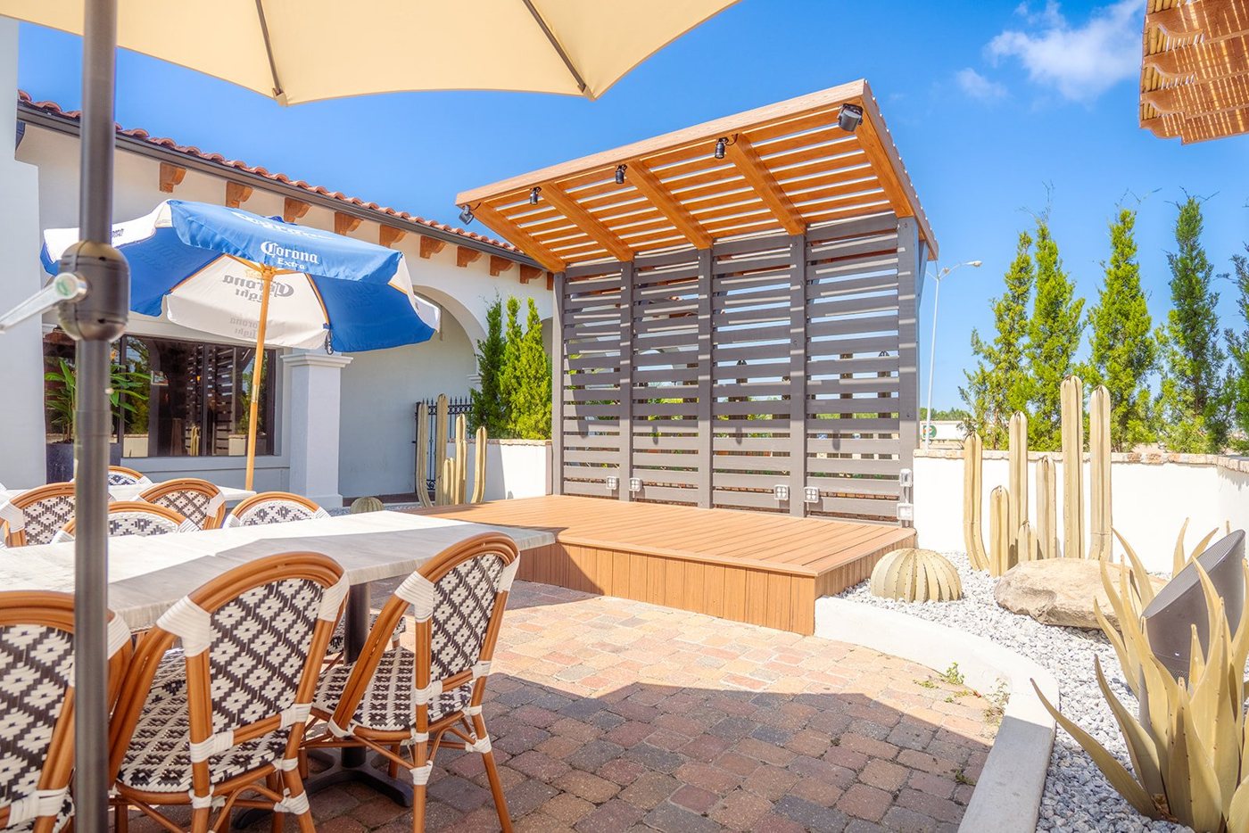 A sunny Aztecas patio with umbrellas and bistro tables