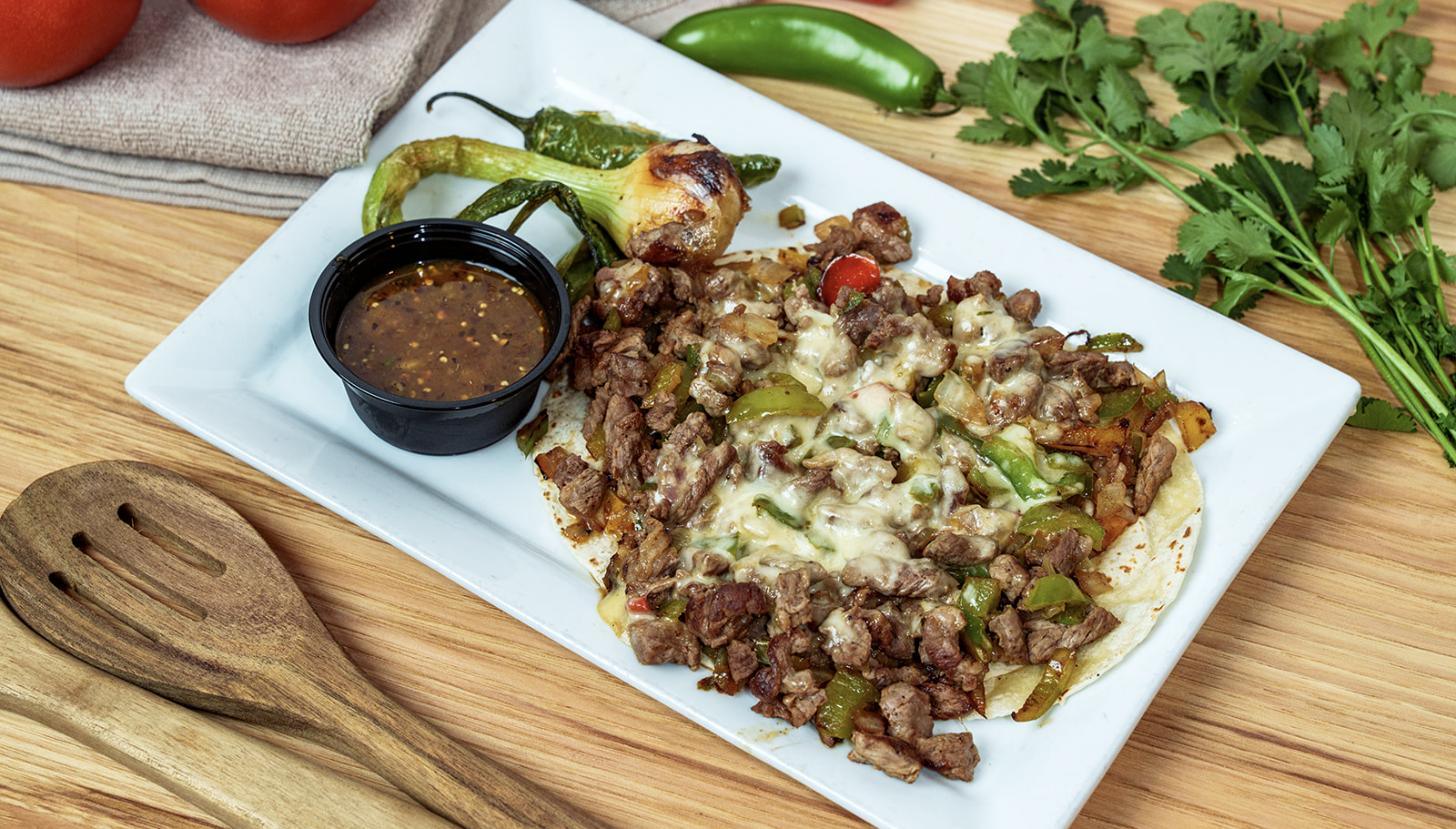 An alambres plate: grilled steak, peppers and onions under melted cheese, with salsa