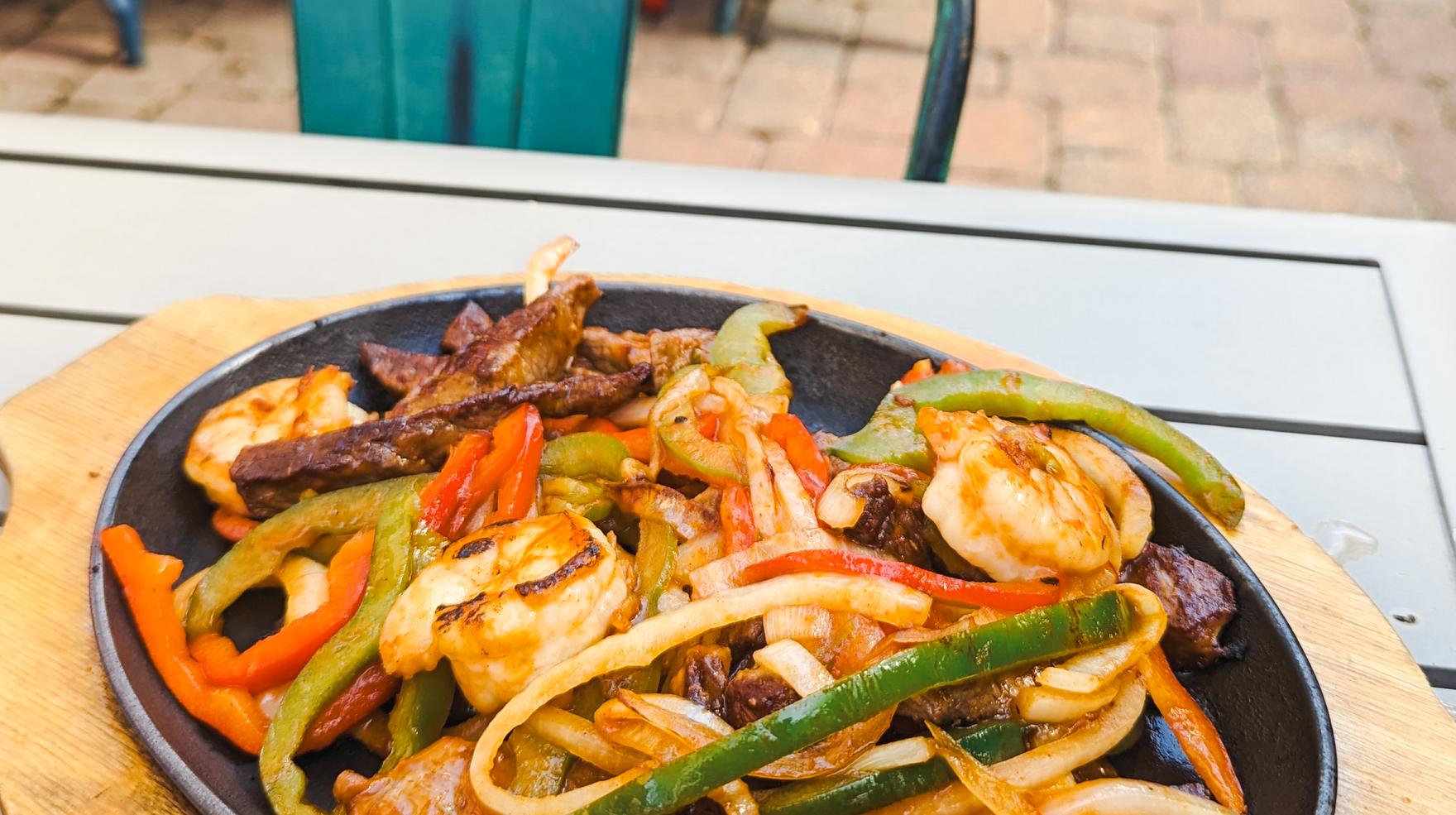 A sizzling skillet of steak and shrimp fajitas with peppers and onions