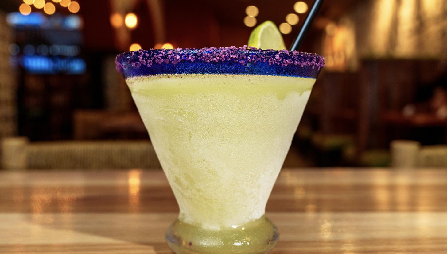 A frozen house margarita with a salted blue rim