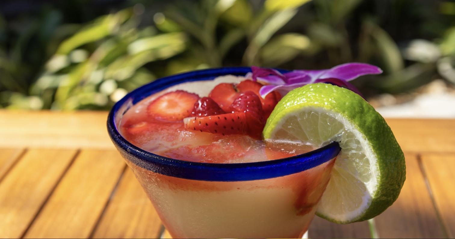 A frozen strawberry margarita with a lime wedge